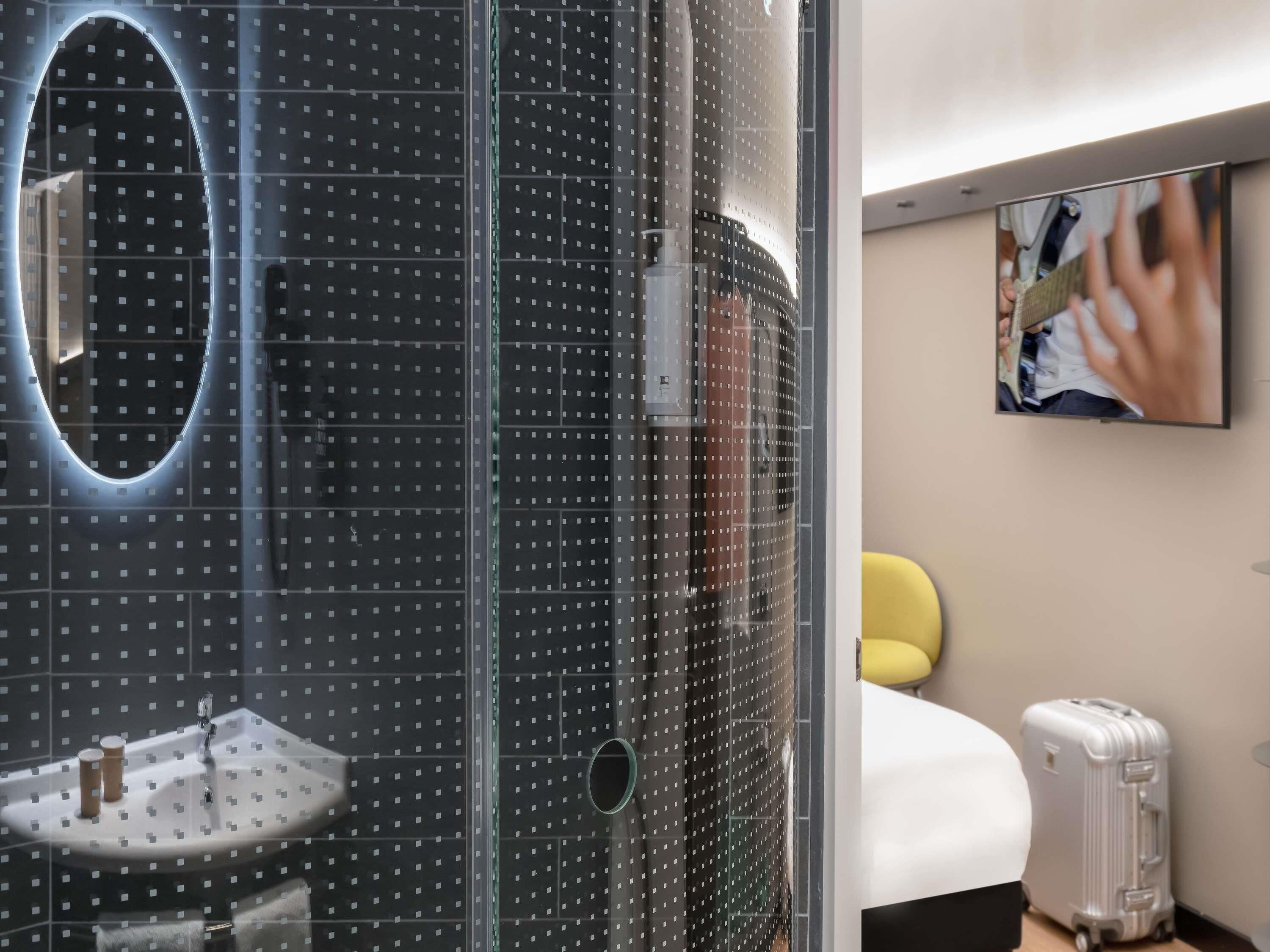 Un baño moderno con cabina de ducha de vidrio, lavabo y espejo.
