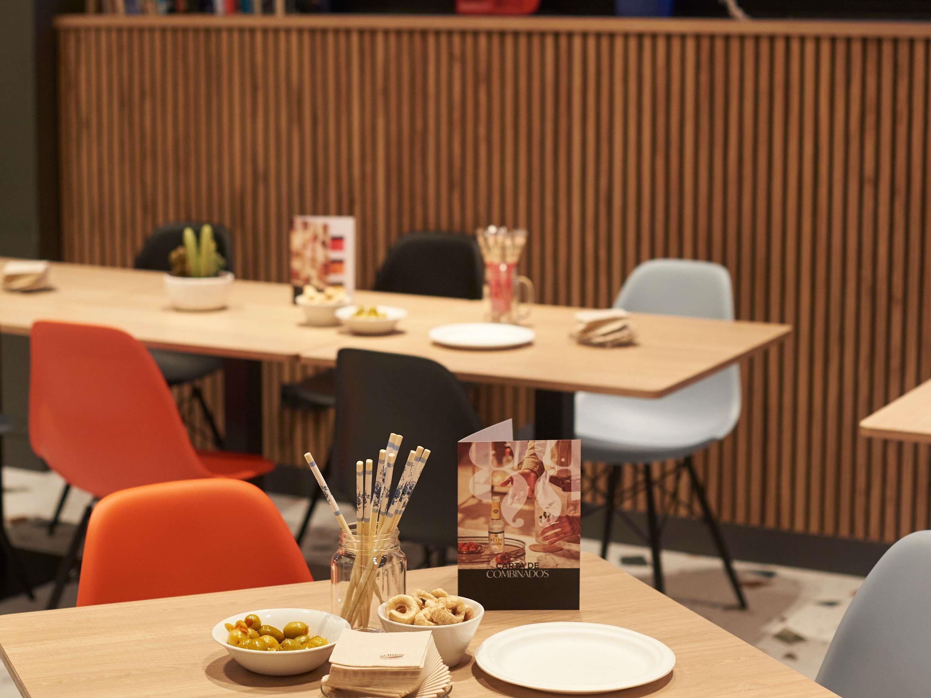 Un comedor con una mesa de madera, sillas y un atril para el menú.