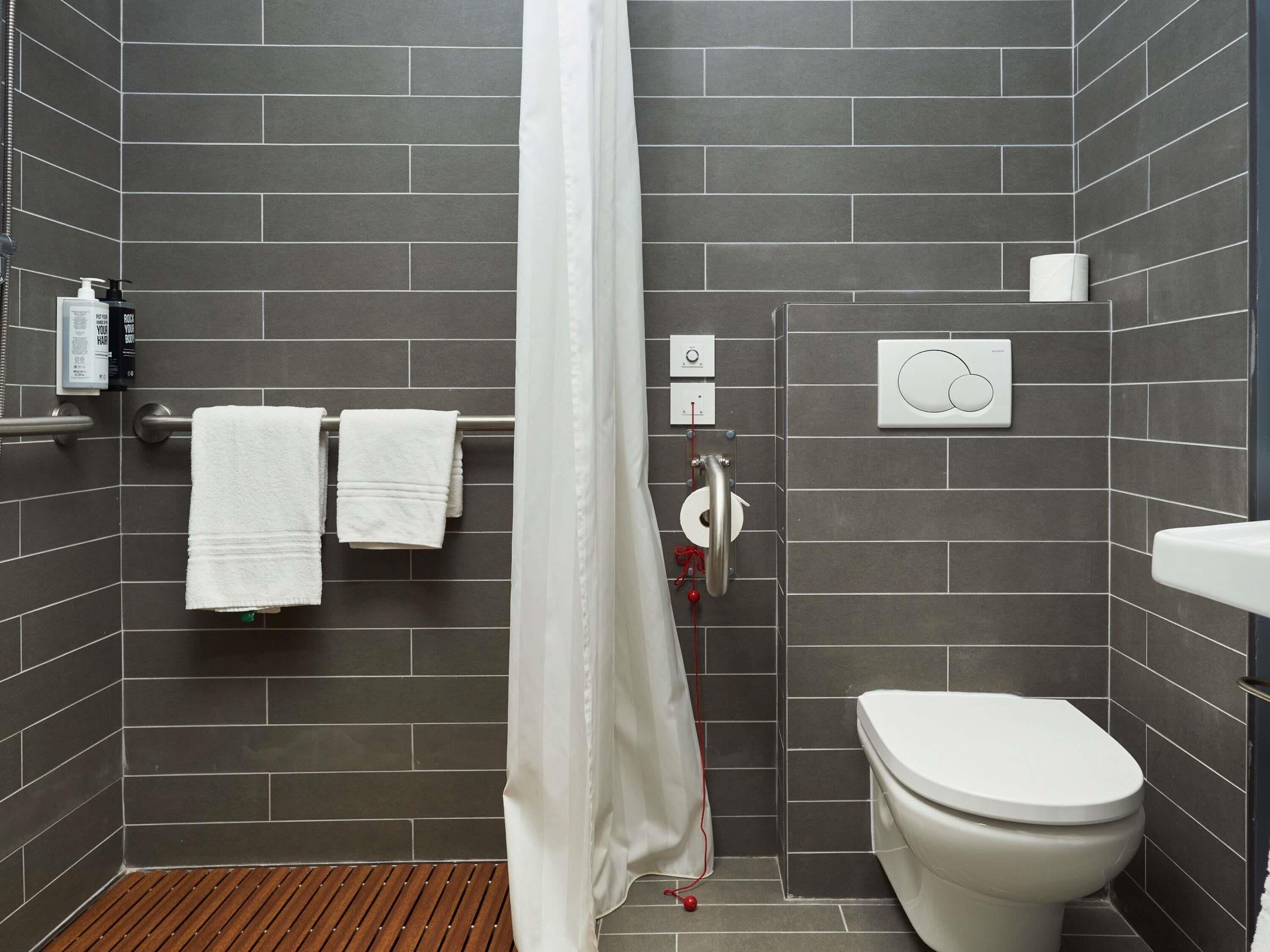 A modern bathroom with a shower curtain, a toilet, and a towel rack with two towels.