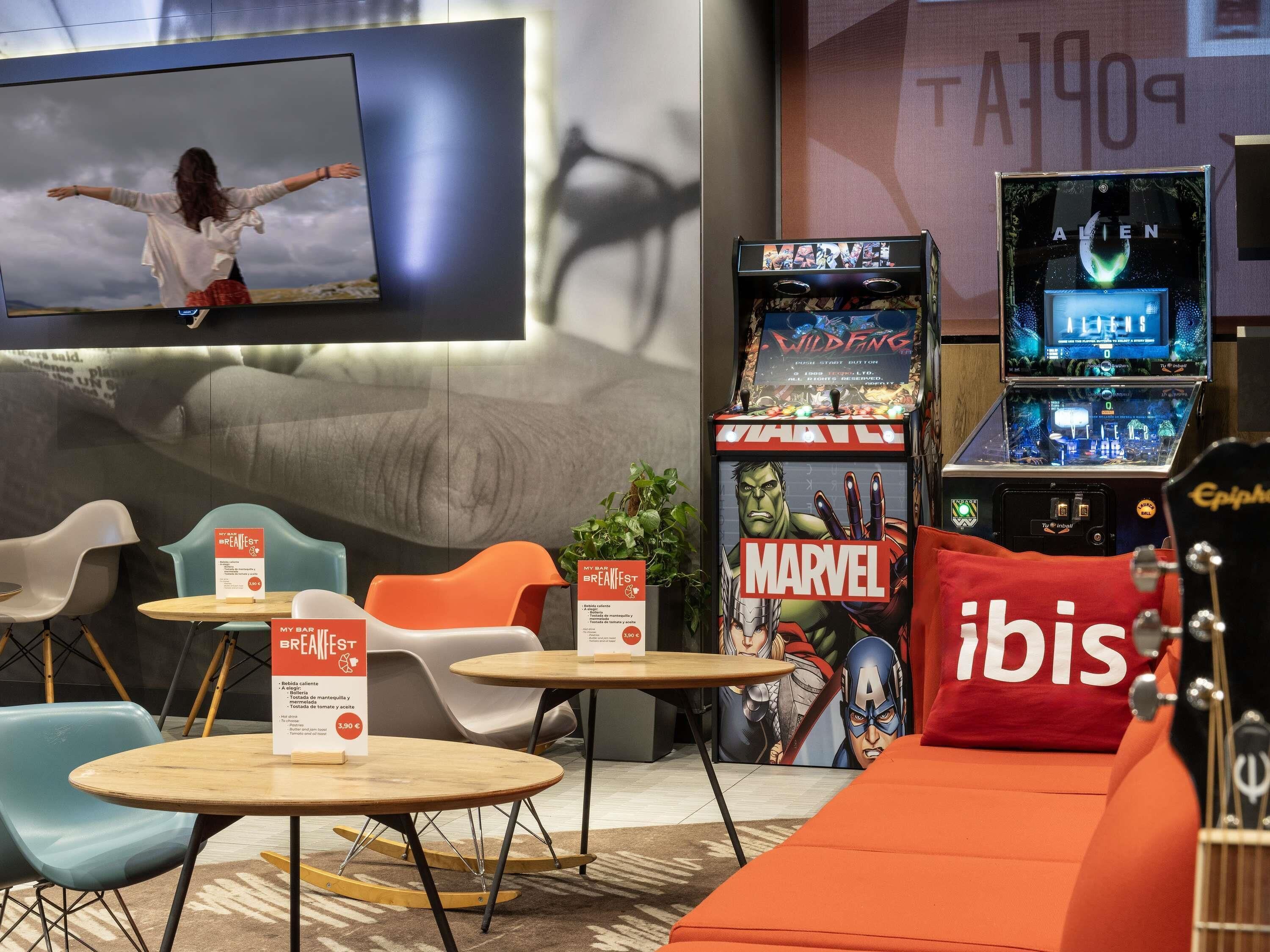 Un'area lounge moderna con posti a sedere, una televisione e giochi arcade.