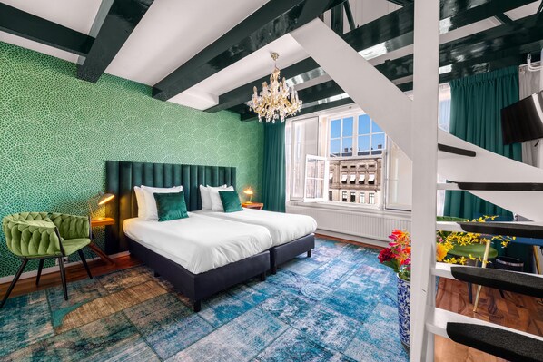 A modern bedroom with a large bed, green textured walls, a chandelier, and a view of a cityscape through a window. - Hotel des Arts (Amsterdam)