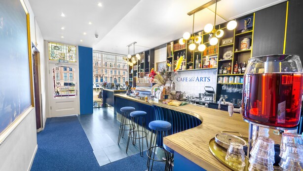 A bar area with stools, a counter, and a large red drink. - Boutique Hotel des Arts (Amsterdam)