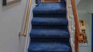 A staircase with blue carpeted steps, a wooden handrail, and a door at the top. - Boutique Hotel des Arts (Amsterdam)