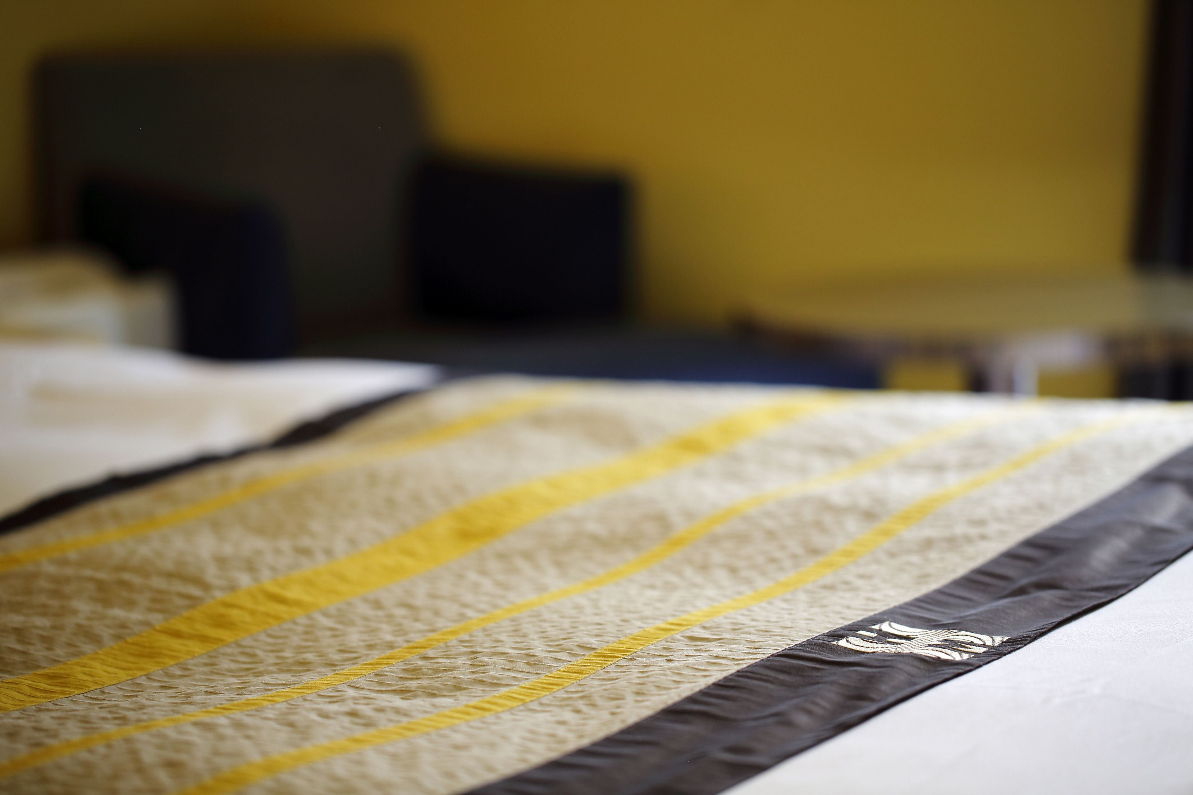 Una cama con una manta a rayas y una almohada decorativa.