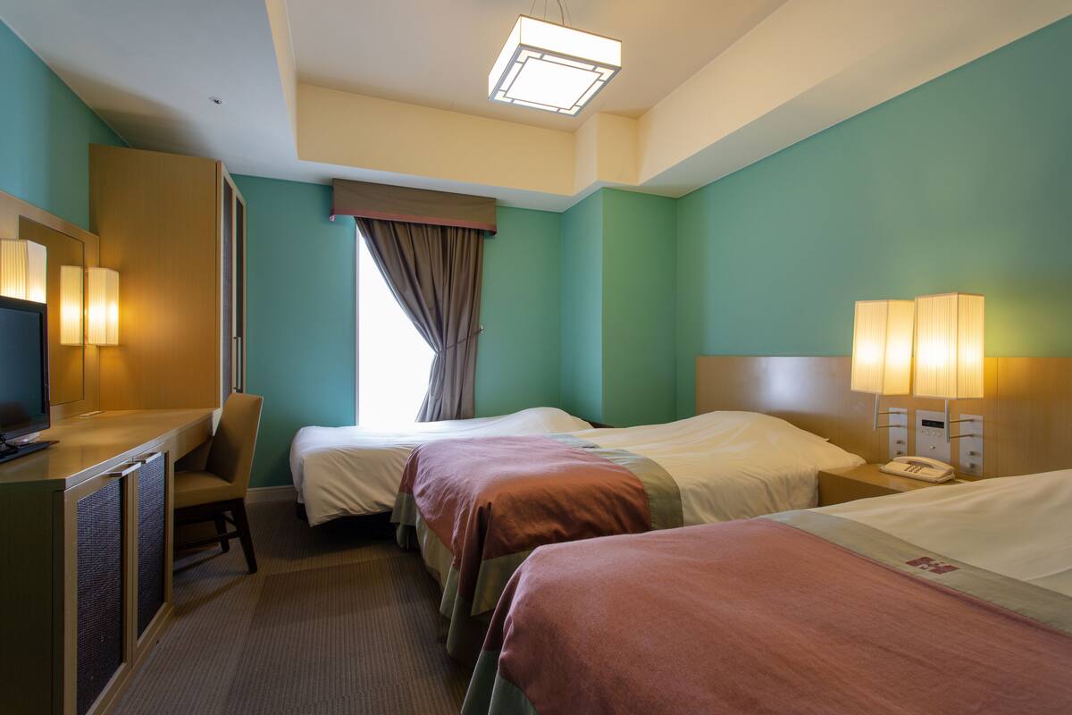 A hotel room with two beds, a desk with a computer, and a TV.