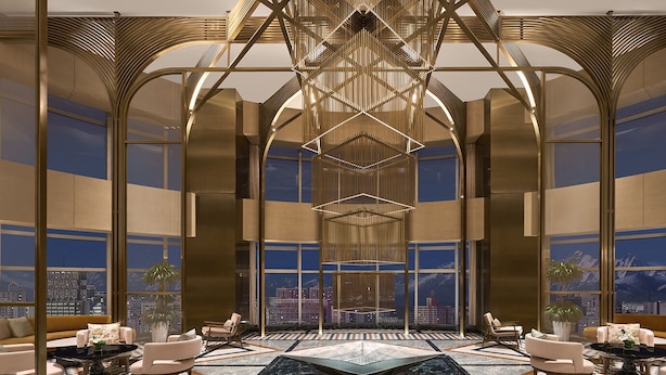 A spacious lobby with a high ceiling, large windows offering city views, and modern furniture.