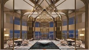 A spacious lobby with a high ceiling, modern chandeliers, and a central water feature.