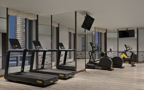 A modern gym with treadmills, elliptical machines, and stationary bikes. - Conrad Urumqi (Ürümqi)