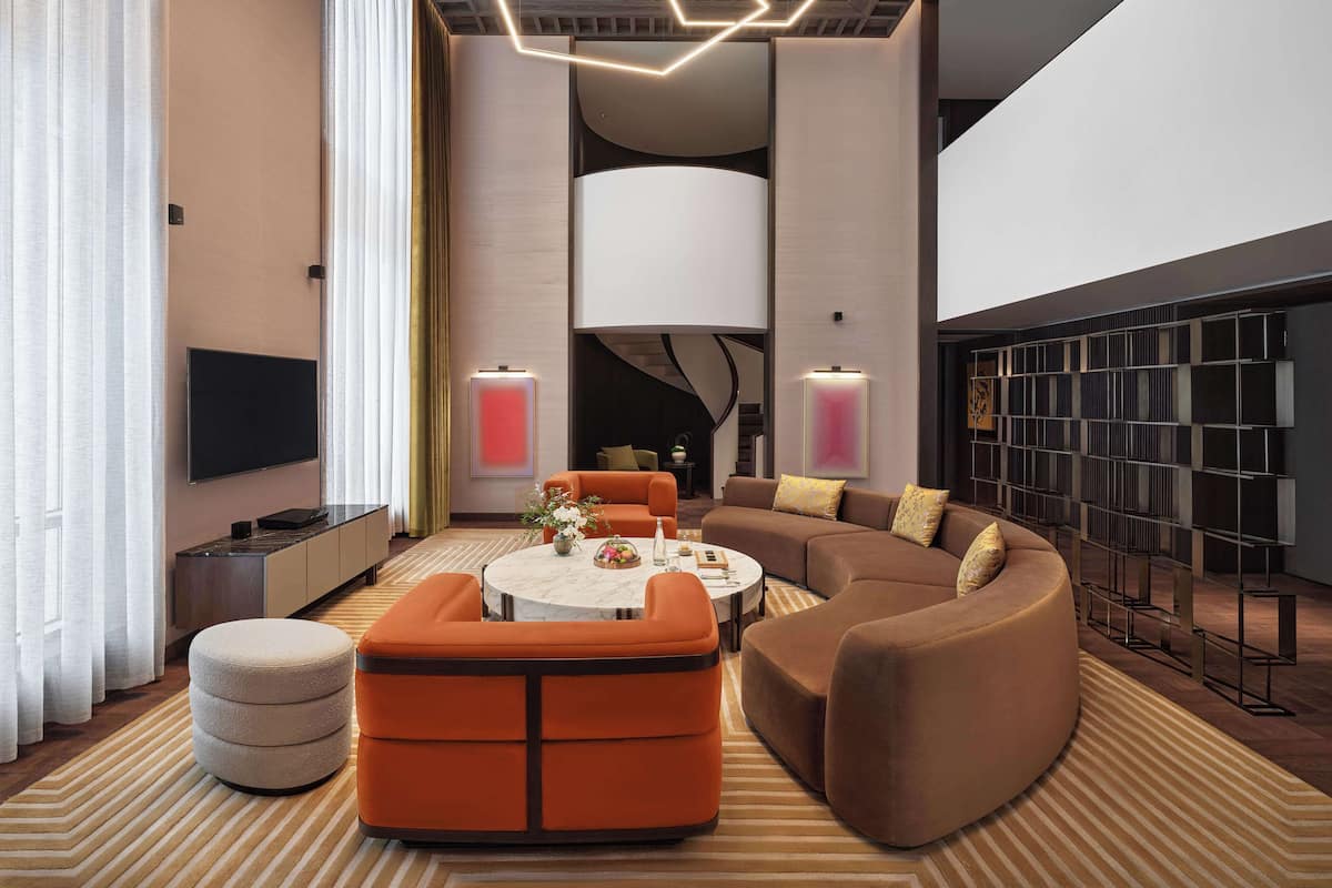 A modern living room with a sectional sofa, a round coffee table, and a large wall-mounted TV.