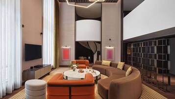 A modern living room with a sectional sofa, a round coffee table, and a large wall-mounted TV.