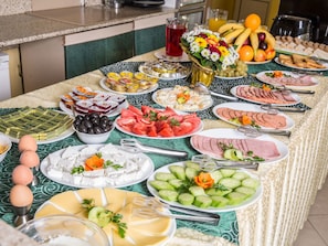 En buffet med forskellige retter, herunder oste, frugt og kød.
