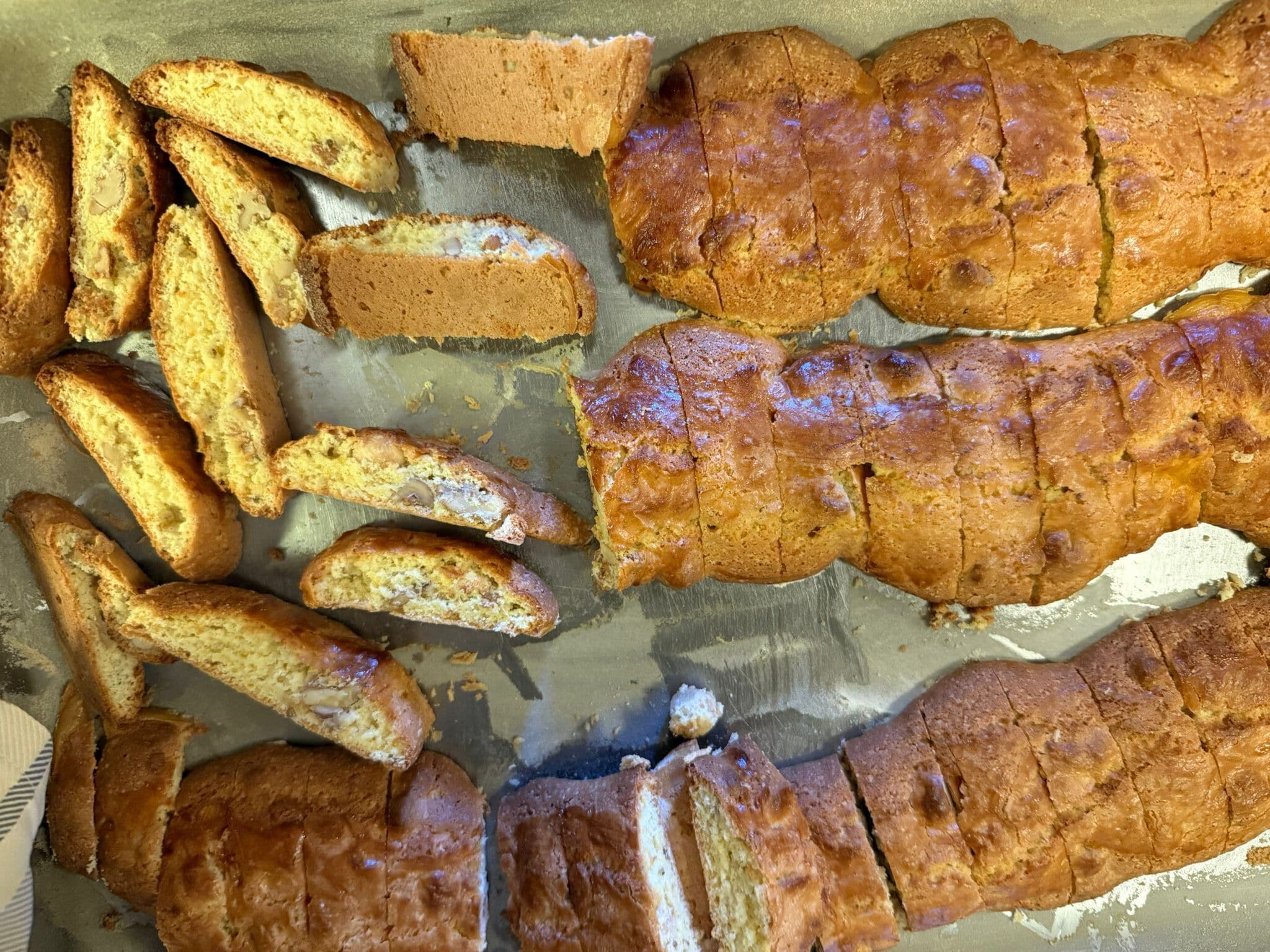 Una hogaza de pan con corteza dorada, cortada en rebanadas, sobre una bandeja para hornear.