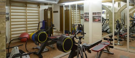 Un gimnasio con equipo de ejercicio, un espejo y piso de baldosas.