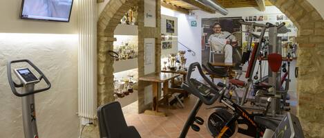 A gym with exercise equipment, a television, and a stone archway.