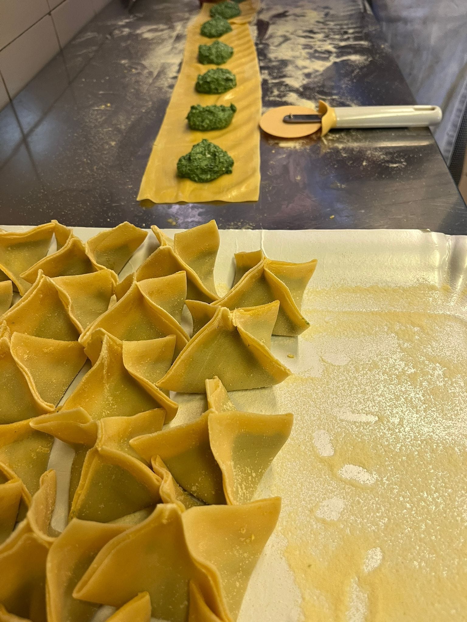 A kitchen with a tray of ravioli and a rolling pin on a countertop.