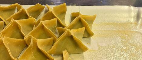 A kitchen with a tray of ravioli and a rolling pin on a countertop.