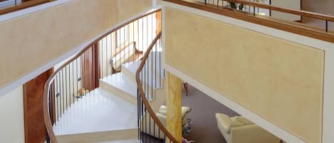 A spacious interior with a central spiral staircase, a seating area with a sofa, and a reception desk.