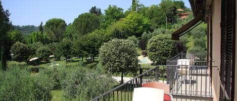 A balcony with a view of a lush garden and trees.