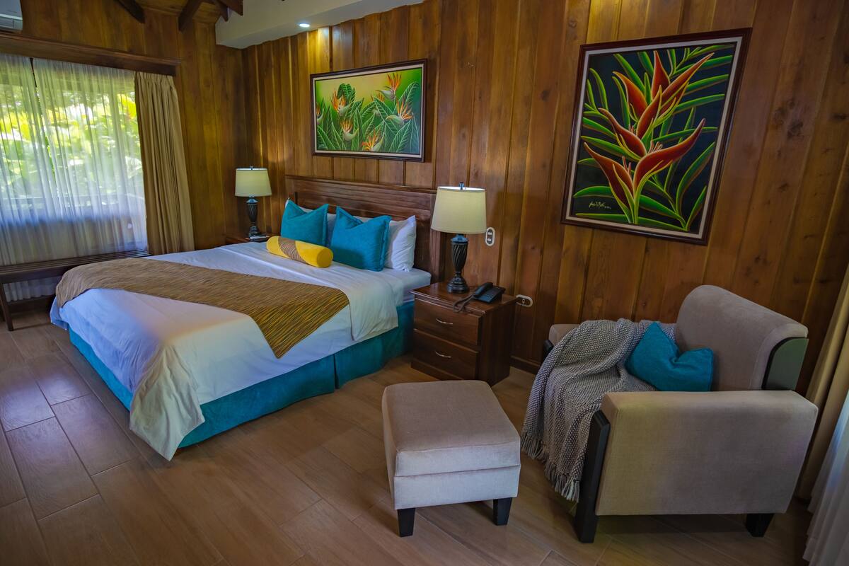 A hotel room with a large bed, two bedside tables with lamps, a chair, and artwork on the walls.