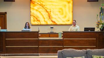 A reception desk with a marble wall art piece above it, a wooden reception desk, and a grey couch in the foreground.