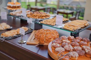 Buffet amb diverses pastes i pa exposats sobre estantes de vidre.