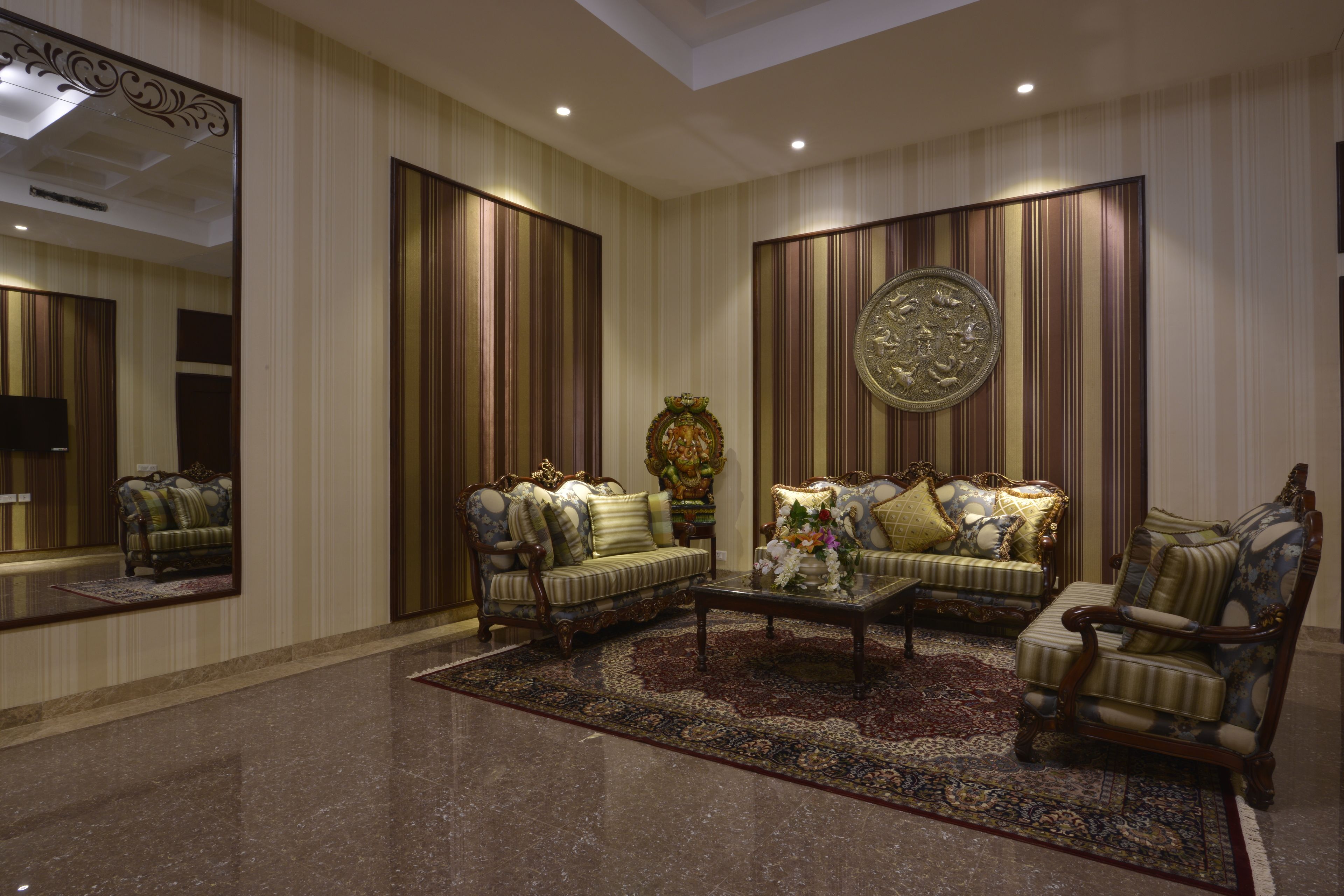 Una habitación amplia con un espejo grande, un conjunto de sofás, una mesa de centro y una alfombra decorativa.
