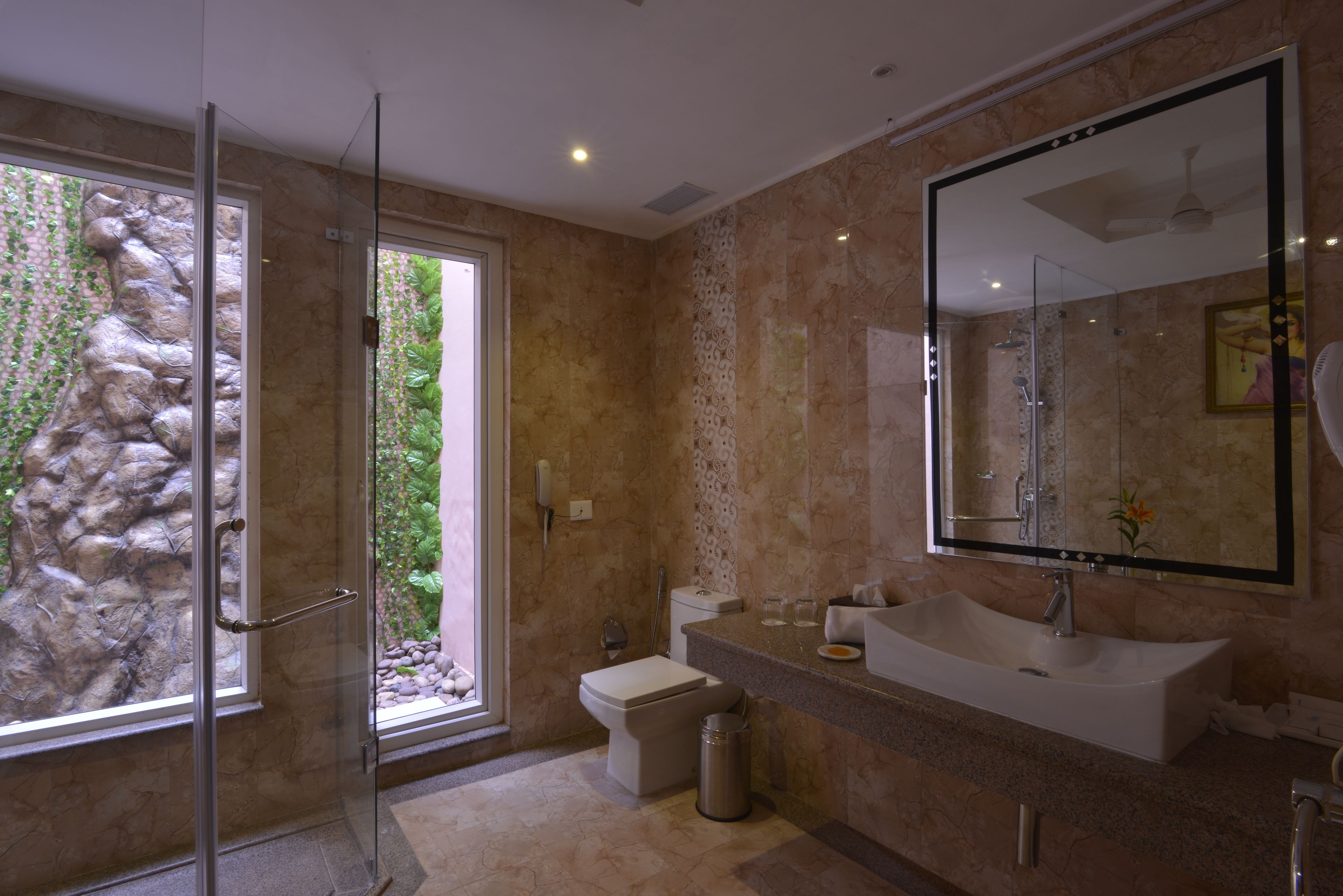 Un baño moderno con cabina de ducha de vidrio, un lavamanos grande y un inodoro.