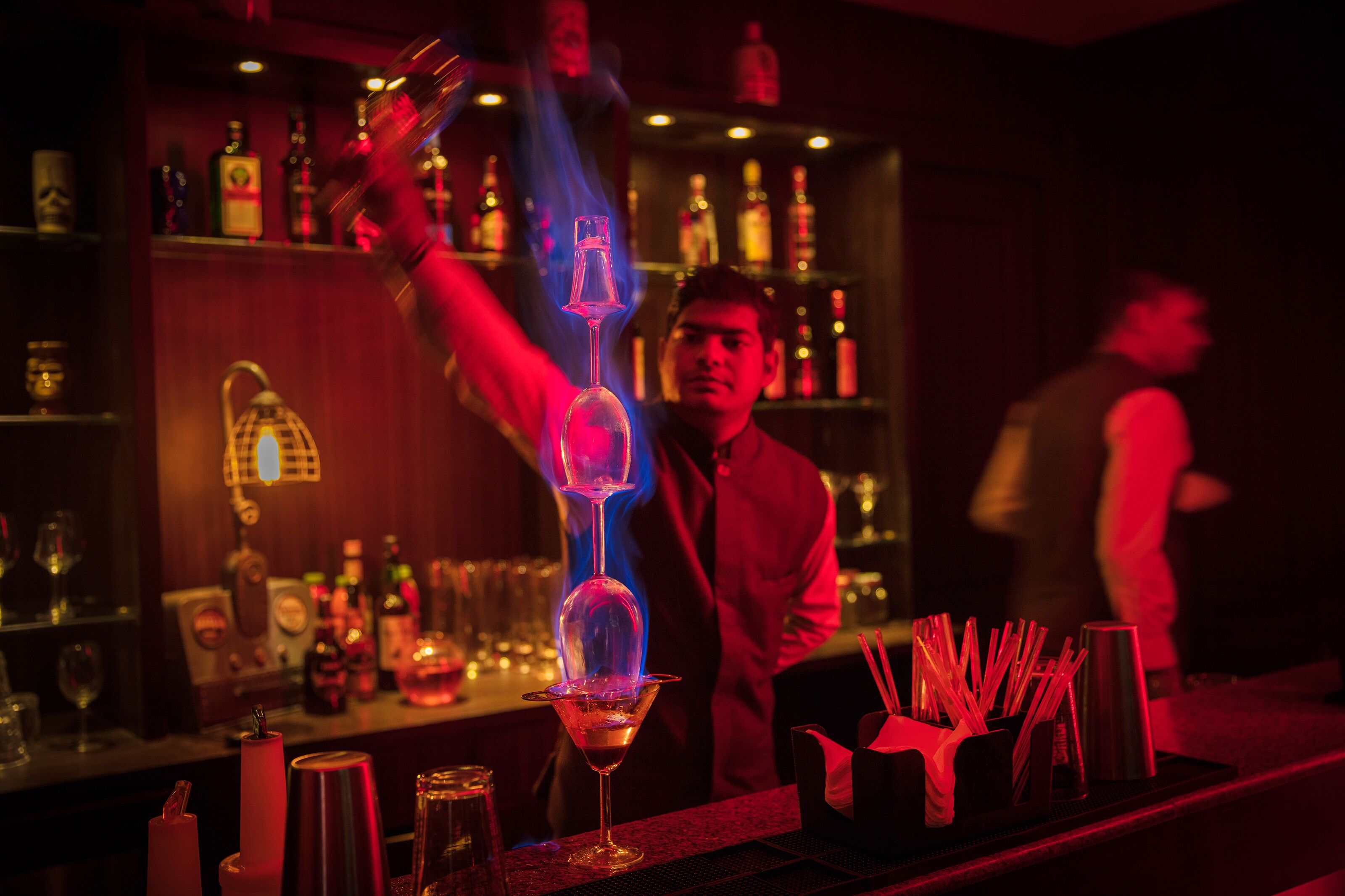 A bar with a bartender performing a flaming trick with a glass.