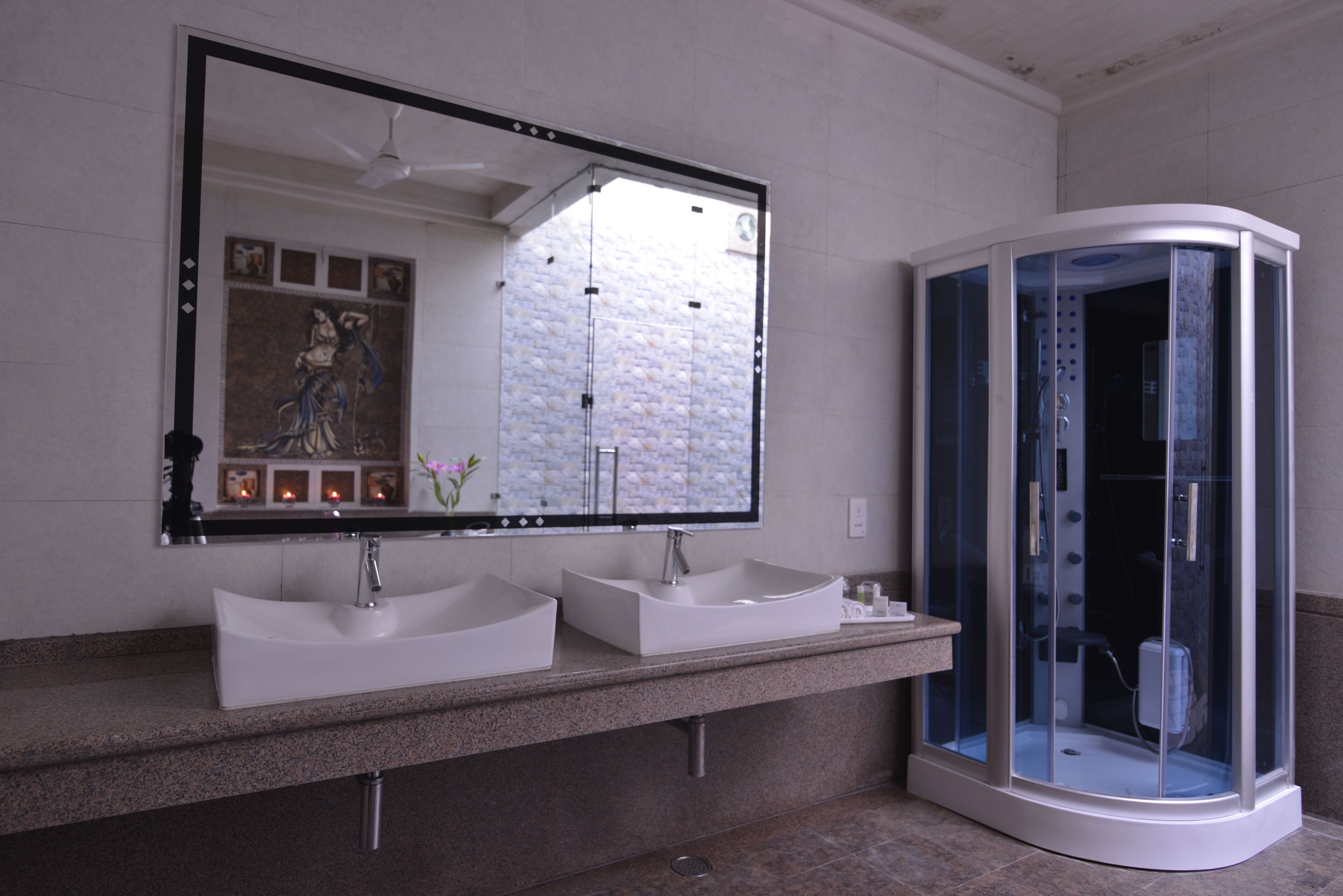 Een moderne badkamer met twee wasbakken, een grote spiegel en een douche met glazen wanden.