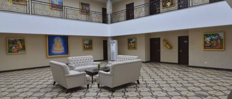 A spacious lobby with a high ceiling, a central seating area with sofas, and a patterned floor.