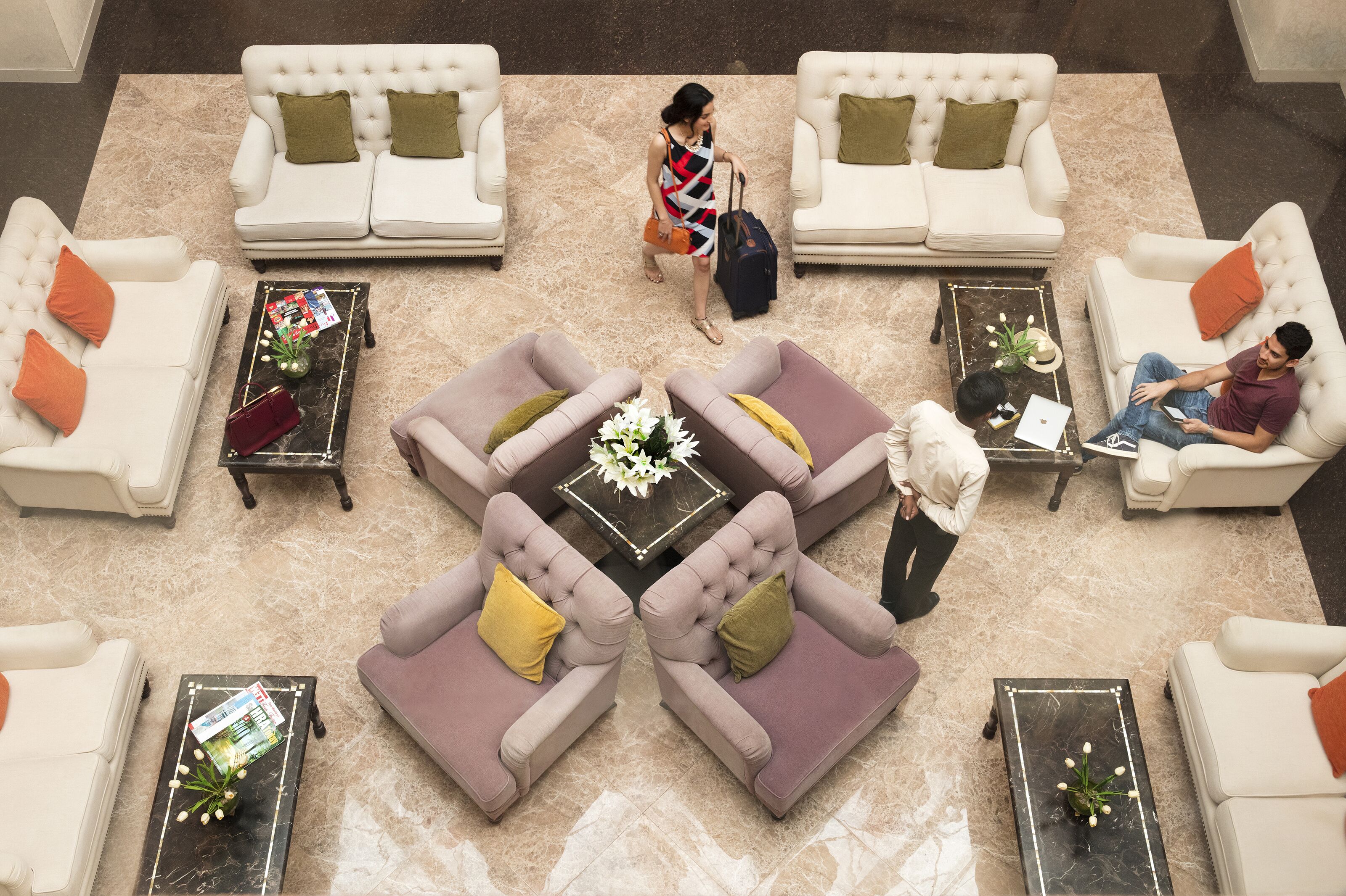Un vestíbulo amplio con varias zonas de estar, incluyendo un conjunto central de sofás y sillones, y algunas mesas con objetos decorativos.