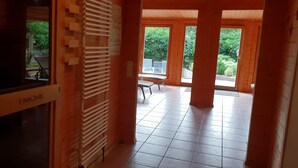 A wooden interior with a bench labeled "FINNJARK," a tiled floor, and a view of an outdoor area with a table and chairs. - Hotel Backenkoehler (Ganderkesee)