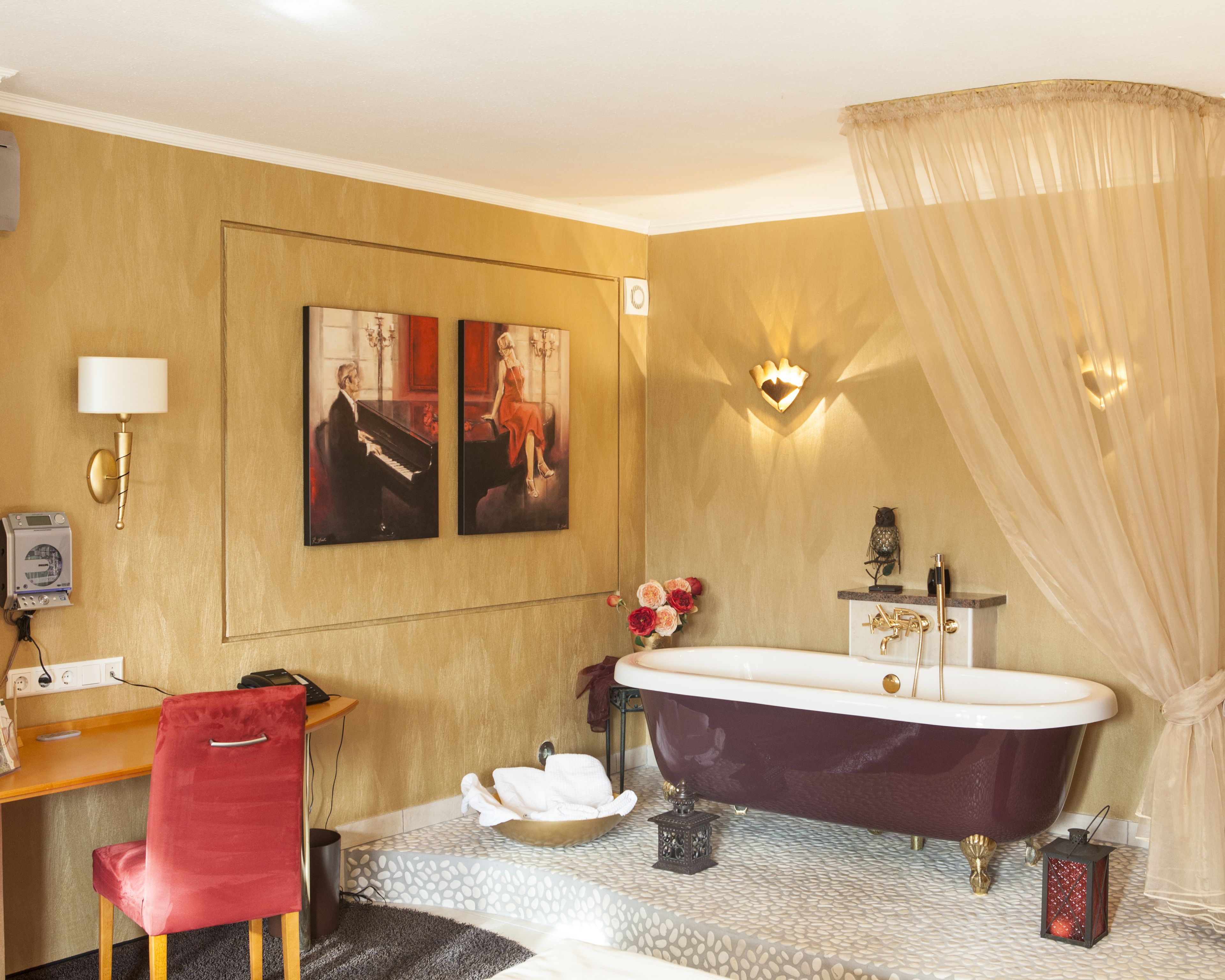 Een badkamer met een bad, een wastafel, een stoel en kunst aan de muur.