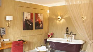 Een badkamer met een bad, een wastafel, een stoel en kunst aan de muur.