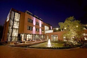Um hotel com vários andares, um pátio central e uma fonte.