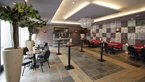 A modern indoor dining area with round tables and chairs, a large potted plant, and a patterned wall. - Hotel Mijdrecht Marickenland (Mijdrecht)