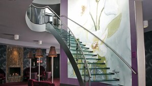 A modern interior with a curved staircase, a fireplace, and a large floral mural. - Hotel Mijdrecht Marickenland (Mijdrecht)