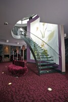 Um interior moderno com uma escadaria curva, uma lareira e um grande mural floral.