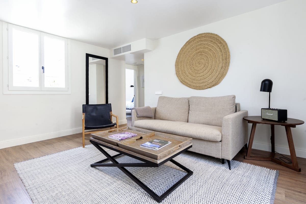 Un salon moderne avec un canapé, une table basse, une lampe et une grande décoration murale tissée.
