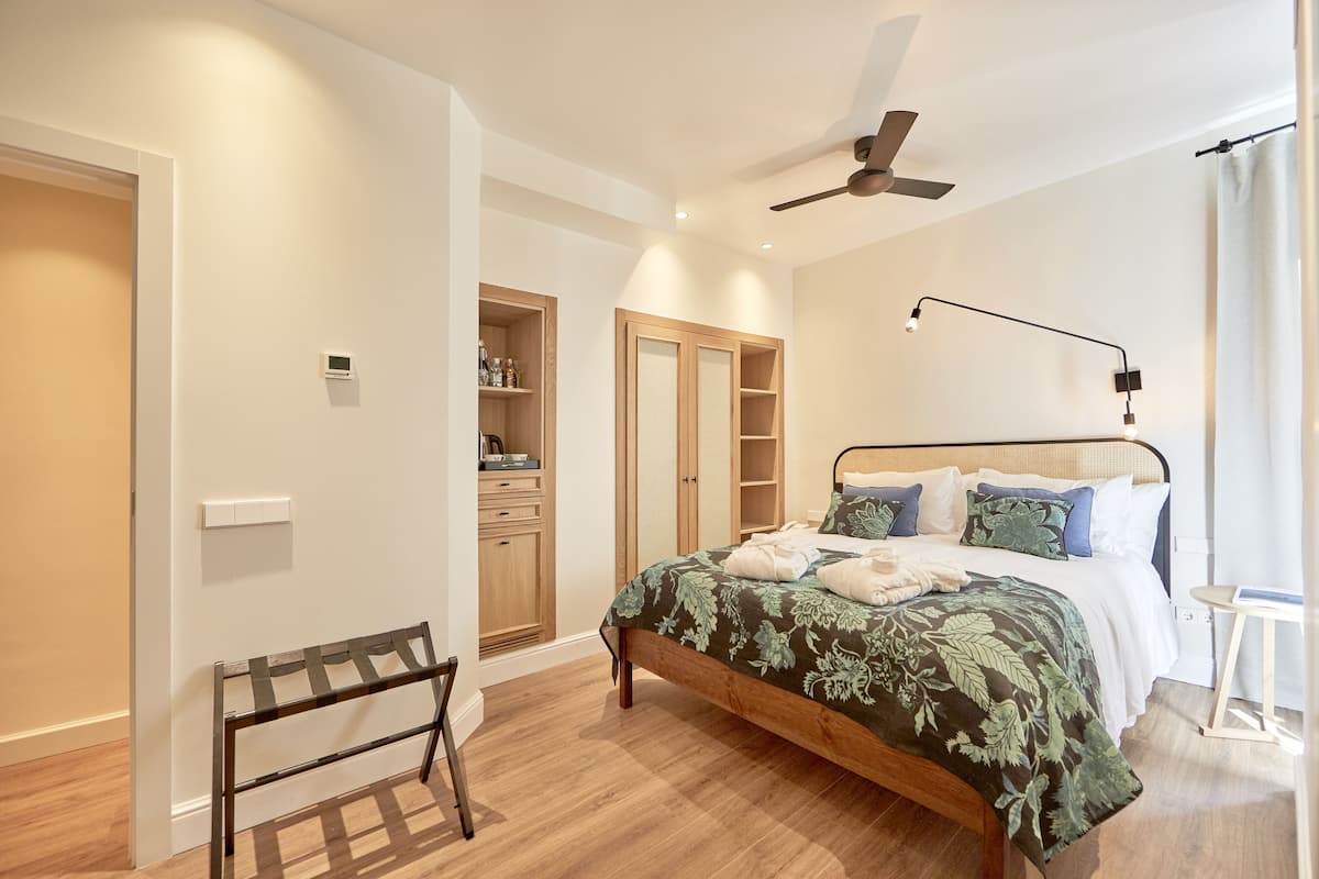 Une chambre à coucher comprenant un lit, une table de chevet, une armoire et un ventilateur de plafond.