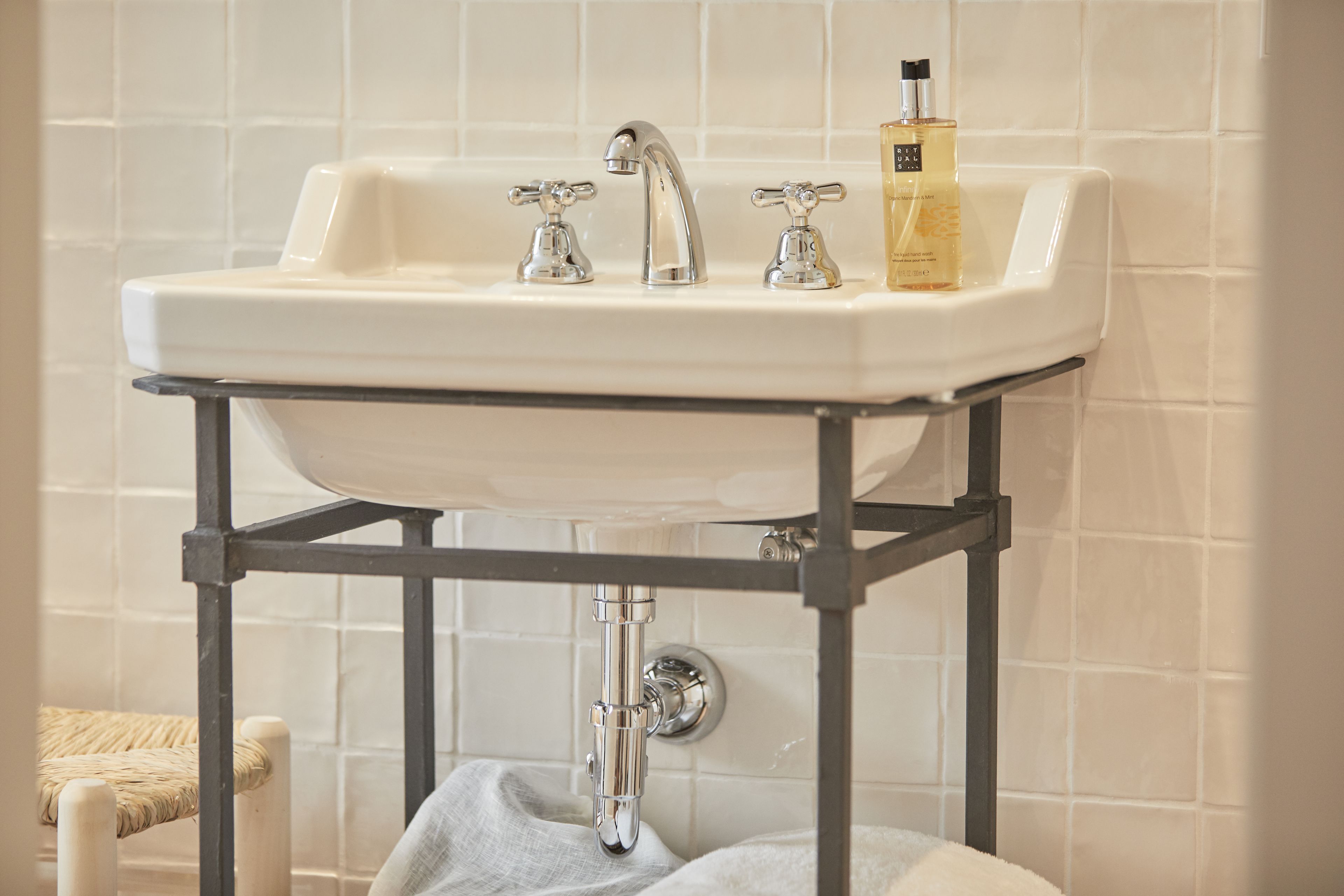 A bathroom sink with a chrome faucet, a soap dispenser, and a bottle of hand soap on the countertop.