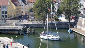 A marina with a sailboat docked, surrounded by buildings and a stone wall.