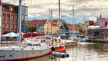 A marina with boats docked, a variety of buildings with different architectural styles, and a cloudy sky.