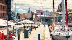 A marina with boats docked, a cobblestone path, and buildings in the background. - Hotel Kontorhaus Stralsund (Stralsund)