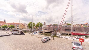 A marina with boats docked, a car, and buildings in the background. - Hotel Kontorhaus Stralsund (Stralsund)