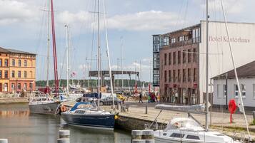 A marina with several boats docked, a modern building labeled "Hotel Kantorhaus," and a brick building in the background.