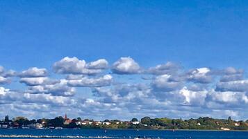 A coastal town with a clear sky, a body of water, and a boat.