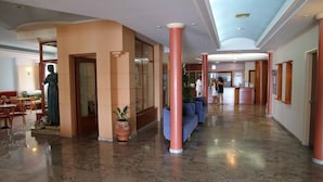 A hotel lobby with a marble floor, a reception desk, and a statue.