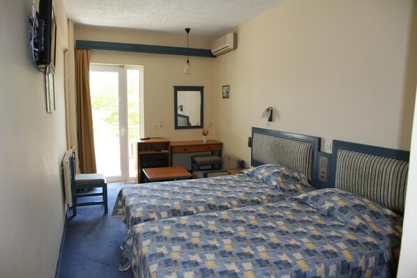 A hotel room with two beds, a desk, a chair, a mirror, and a television.