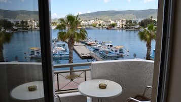 Ein Balkon mit zwei Tischen mit Blick auf eine Marina, in der Boote und Palmen zu sehen sind.